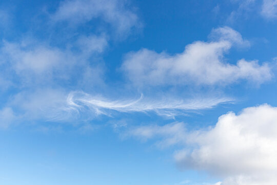 Wispy & fluffy white clouds in a blue sky at Caleta del Mojon Blanco near Orzola on the north coast of the Canary Island of Lanzarote, Spain