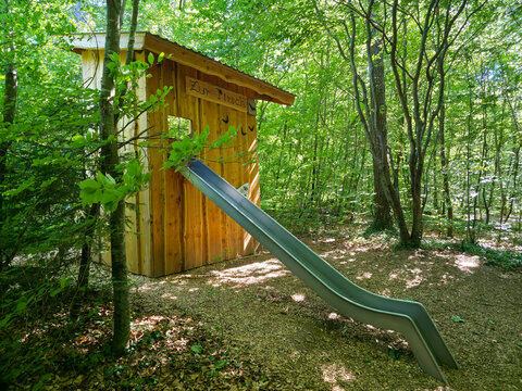 germany, wooden forest hut with slide creating magical play experience along enchanting woodland adventure trail