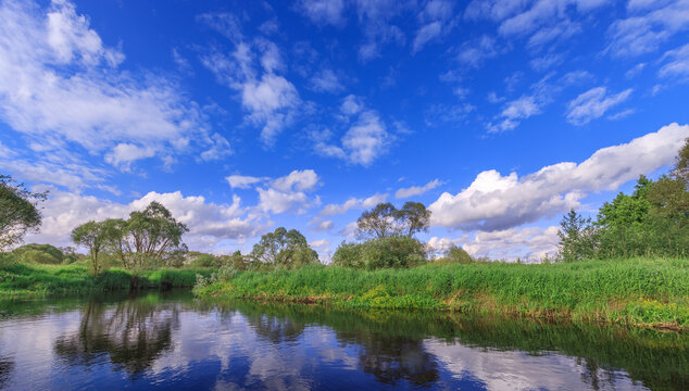 Calm river mirrors sky's blue hues