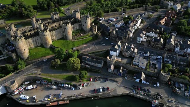 Conwy Castle and the surrounding town. You can see the castle walls and the buildings next to the water. The view captures everyday life in Conwy