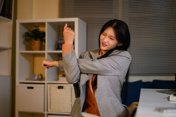 Asian Businesswoman Stretching Wrist at Office Desk to Relieve Office Syndrome Pain During Work © Prathankarnpap