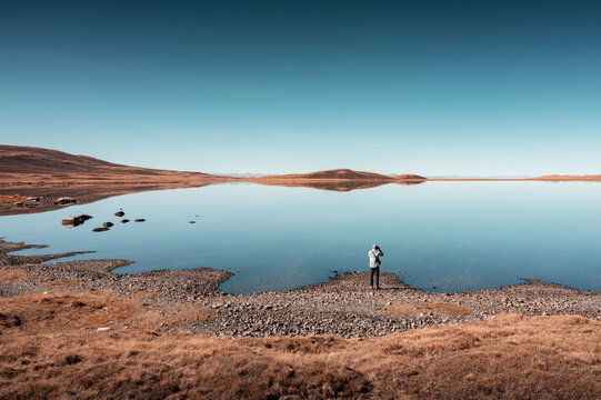 A tourist looks into the distance by the lake