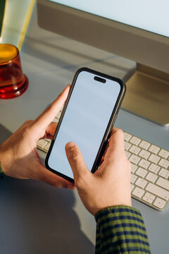 The man uses a computer and a mobile phone with a white screen