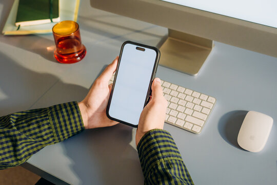 The man uses a computer and a mobile phone with a white screen