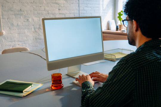 A man uses a computer with a white screen 