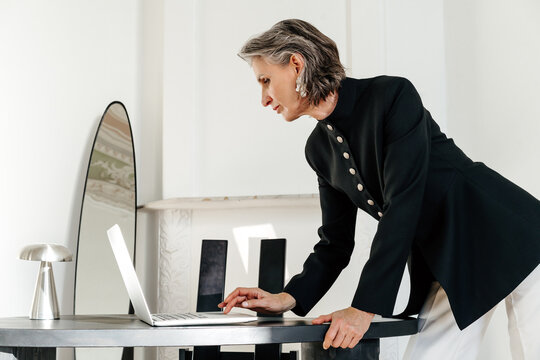 Mature Woman Working on Laptop at Stylish Minimalist Table