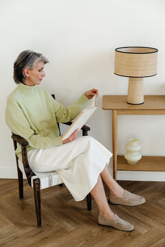 Mature Woman Reading Book in Minimalist Living Room