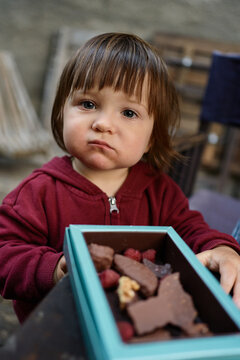 Child Holds a Box of Chocolate and Berries in a Casual Setting