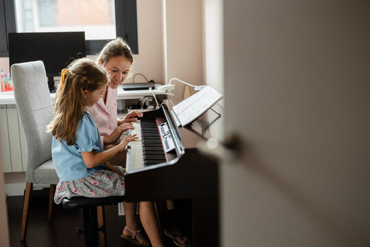 Young girl learning piano with music instructor