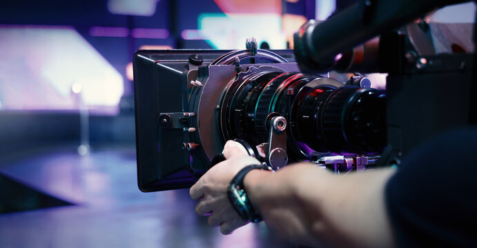 Behind the scenes of movie shooting or video production at studio with high quality camera gimbal or tripod equipment set up and professional film crew team or camera operator with flare lighting.