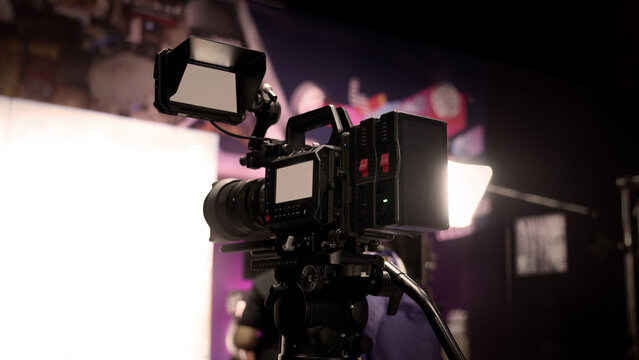 Behind the scenes of movie shooting or video production at studio with high quality camera gimbal or tripod equipment set up and professional film crew team or camera operator with flare lighting.
