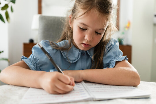 Young girl concentrating on writing school homework
