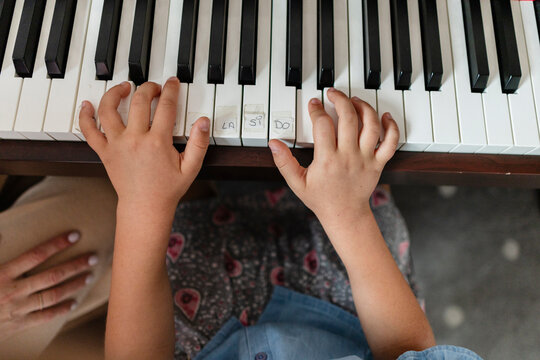 Child's hands learning notes on piano keyboard