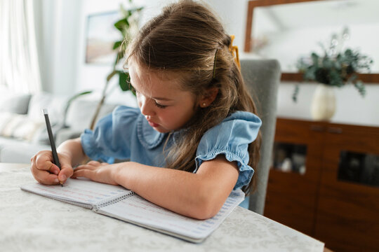 Girl concentrating on writing homework in notebook
