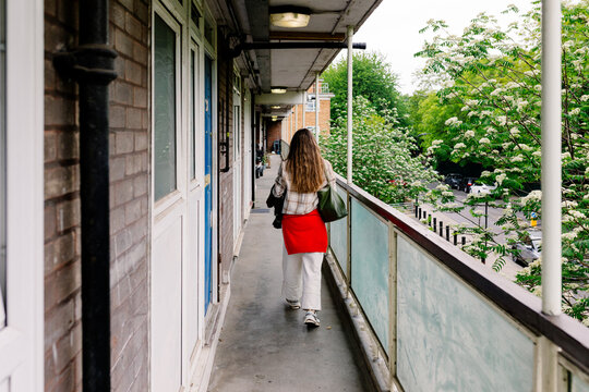 Woman seen from behind, walking down an outdoor hallway at a hotel