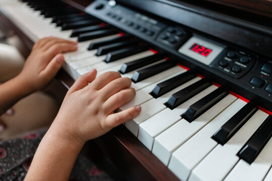 Child hands learning playing digital piano musical instrument