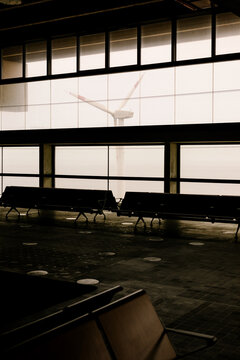 Empty airport lounge shows rows of seating near large window