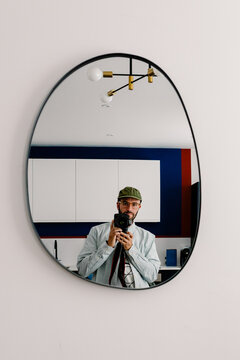 Mirror selfie of a photographer holding his camera in a modern kitchen