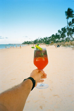 Anonymous person's analog POV holding a refreshing tropical drink