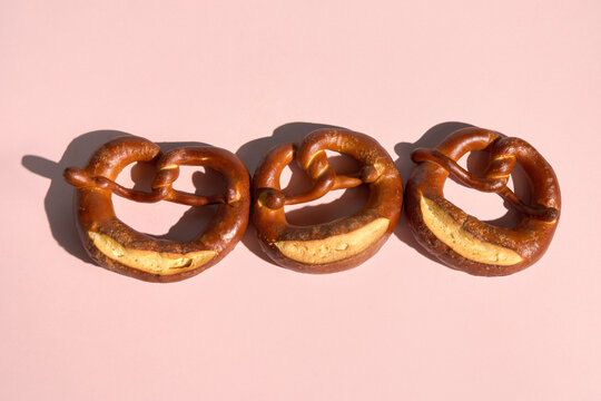 Row of Three Freshly Baked Pretzels on Pink Background with Copy Space