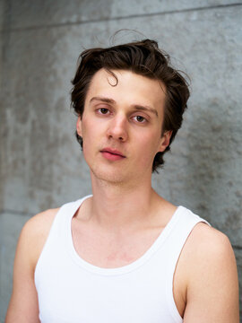 Portrait of a Young Man in a Simple Tank Top Against Gray Background