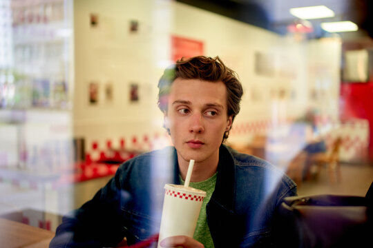Man Sitting in Cafe Holding a Drink During Daytime