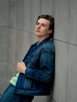 Man Leans Against a Wall in a City Setting During the Day