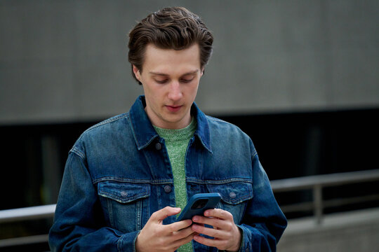 Young Man Using Smartphone in City Setting During Daytime