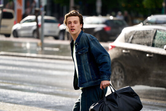 Young Man Walks on Street Carrying a Bag in Wet Weather