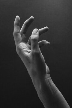 Hand gesture shown against a dark background 