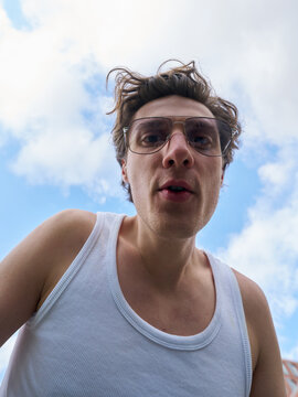 Man Looks up at Camera With Blue Sky in the Background