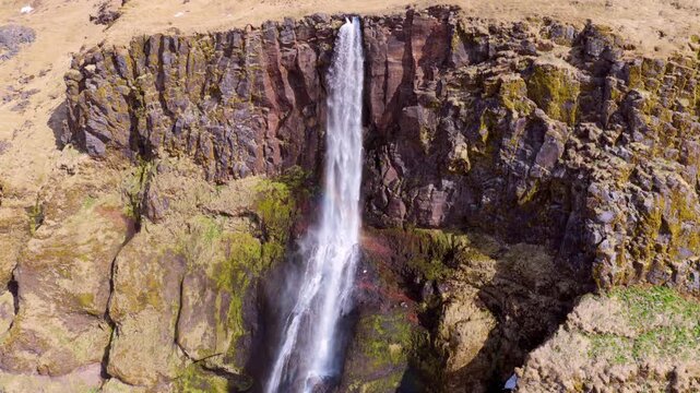 Waterfall Bjarnarfoss finale over canyon cliff in remote landscape. Iceland