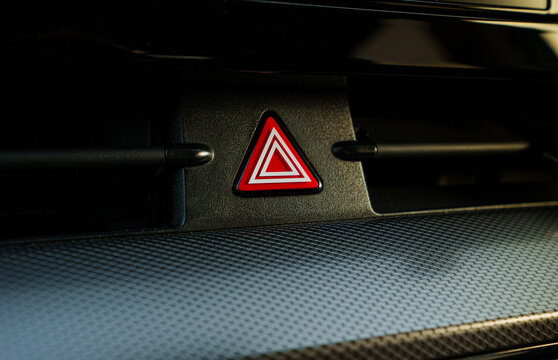 Glowing red hazard light button on car dashboard, emergency warning flasher switch in vehicle cabin
