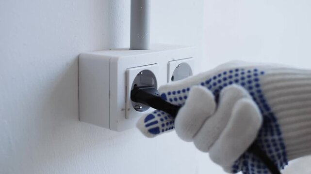 Closeup Of Skilled Electrician Securing Power Cable Into Wall Socket With Safety Emphasis