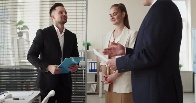 Business team meeting with contract negotiation partners. They review documents and discuss terms in a bright office, collaborating to reach agreement. Clear concept of contract review and deal.