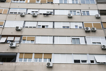 Apartment block facade with multiple air conditioning units. Residential housing exterior background. Urban building architecture showing windows balconies and cooling systems. © Paweł Michałowski