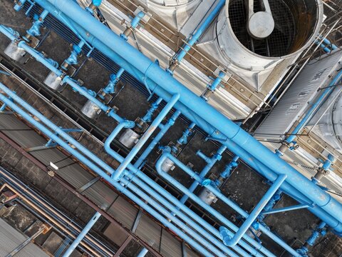 Close up aerial view of industrial blue cooling pipes and ventilation fan.