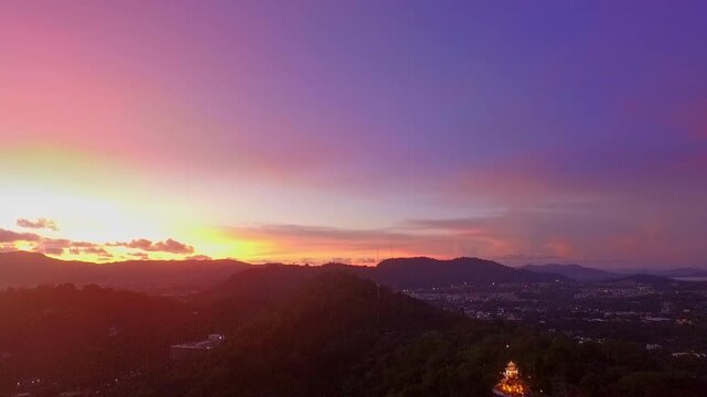 Aerial view of Sunset above Khao Rang viewpoint. view of a town nestled among lush green mountains at sunset, with a Pavilion structure perched on the hillside at Phuket town at Dusk