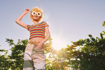 Obraz premium Woman lifestyle portrait with retro film color in sunny outdoors, a playful fashion scene, striped top and shorts under bright sunlight, smiling carefree in garden.