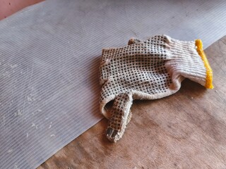 Obraz premium Well-worn work glove casually resting on a corrugated surface next to a wooden floor, signaling a break from manual labor or home improvement task