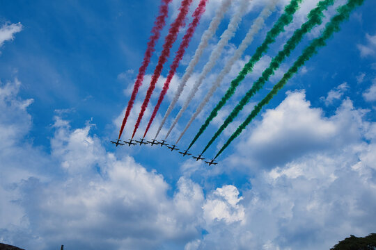 Italy , Aerobatic jet team performing precision formation flight. High-speed military aircraft trailing colored smoke during airshow demonstration.
