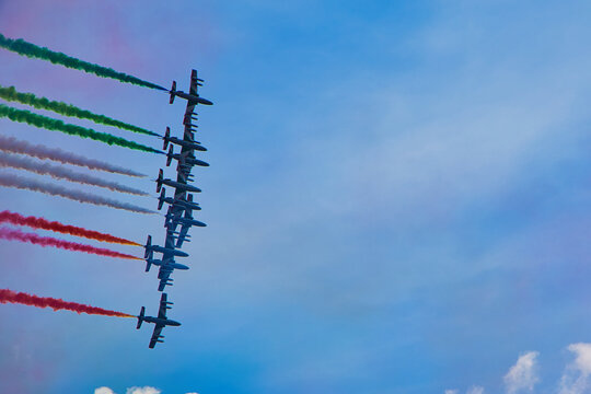 Aerobatic jet team performing precision formation flight. High-speed military aircraft trailing colored smoke during airshow demonstration.