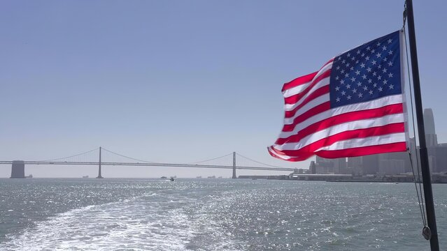 American flag flying on a beach with a bridge in the background
