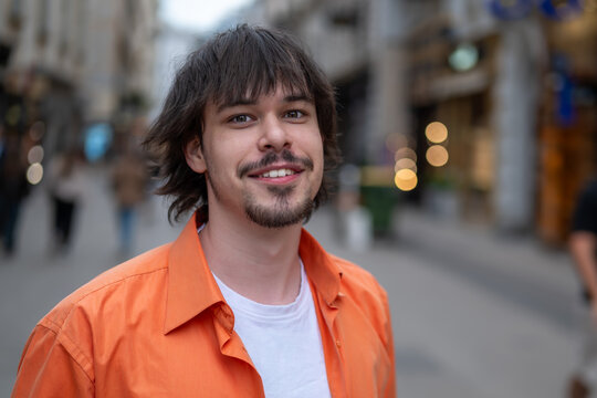 Twenty five year old young man smiling while walking along a city street.