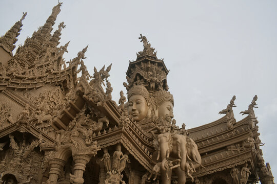 detailed angle of intricate hand carved brahma faces and elephant sculptures on the roof of sanctuary of truth wooden temple in pattaya thailand