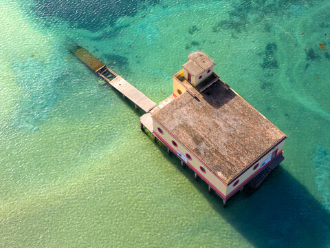 Aerial view of the historic Antiga estacao Salva-Vidas da Fuseta, a former lifeboat station on stilts above the turquoise waters in Fuseta, Faro District, Portugal.