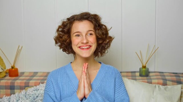 smiling young woman with braces and curly hair full of anticipation, eagerly awaiting a good surprise, expressing joyful expectations and excitement