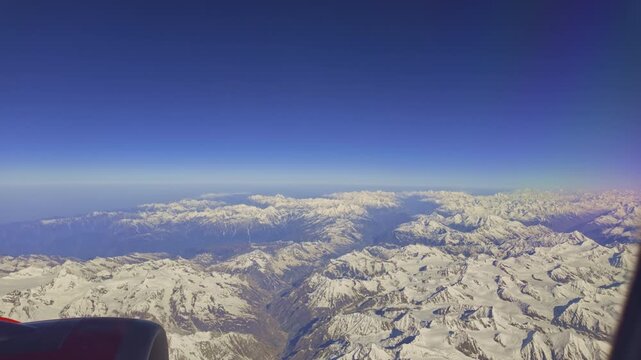 A rugged of Himalayan mountain ridge blanketed with patches of snow under a vivid blue sky, capturing the stark beauty and raw terrain of a high-altitude alpine landscape. nature dramatic textures.