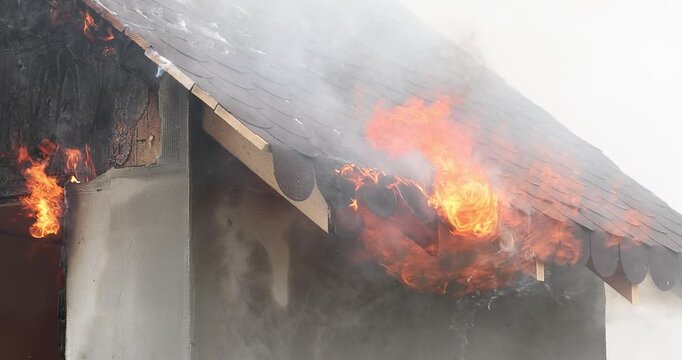 A 4K slow motion movie with a miniature house burns in a controlled manner to observe the behavior of different materials and untreated wood against fires.