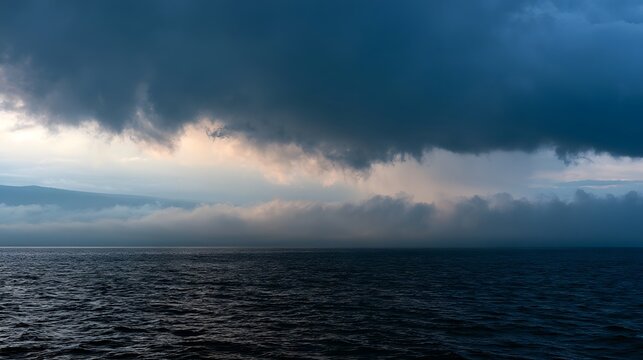 Glistening storm clouds roll over the ocean creating a dramatic and misty seascape horizon